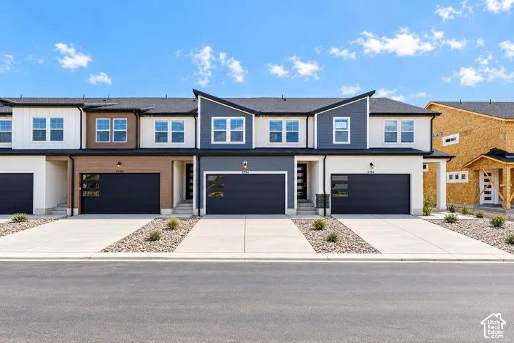 Modern townhome facade featuring multi-tone siding, black-frame windows, and dark garage doors with frosted glass inserts