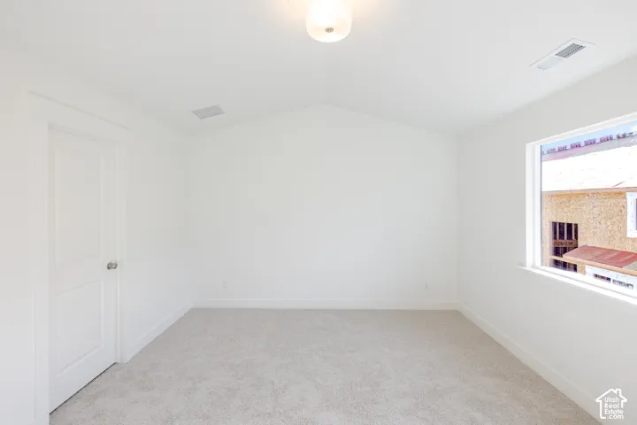 Bright interior with light-colored carpeting, a white paneled door, and a single window