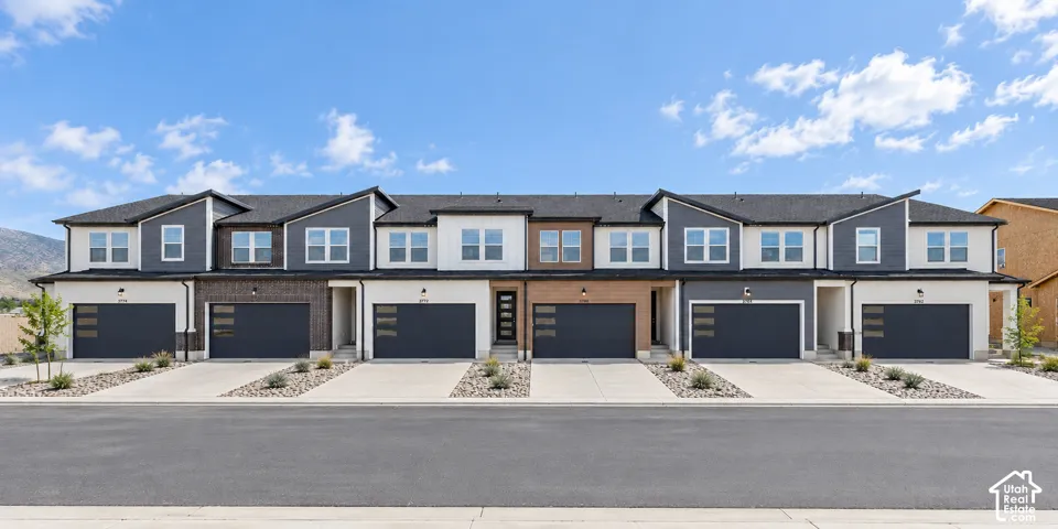 Contemporary townhome exteriors featuring varied siding materials, attached garages, and a paved driveway