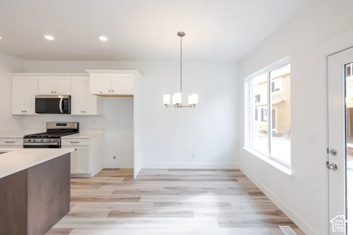 Modern kitchen featuring white cabinetry, stainless steel appliances, and a central island with a light-toned countertop