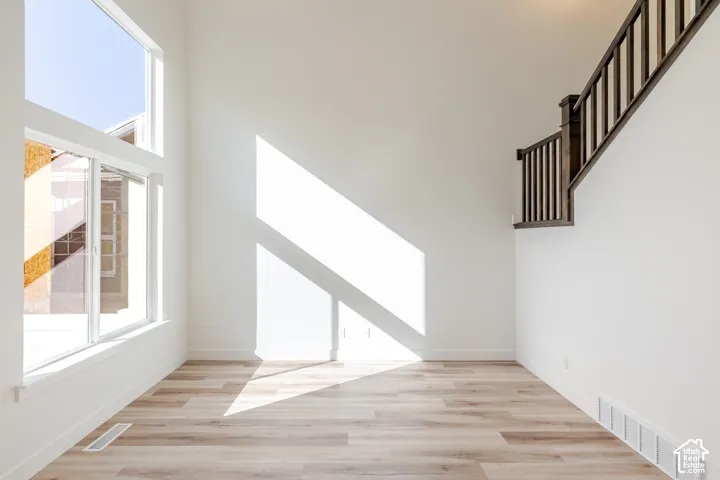 High ceilings, wood-finish flooring, two-story window, white walls, and a dark wood staircase