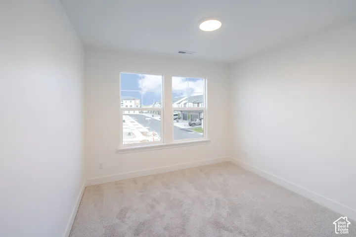 Recessed ceiling light, two windows with white frames, wall-to-wall carpeting, and white painted walls
