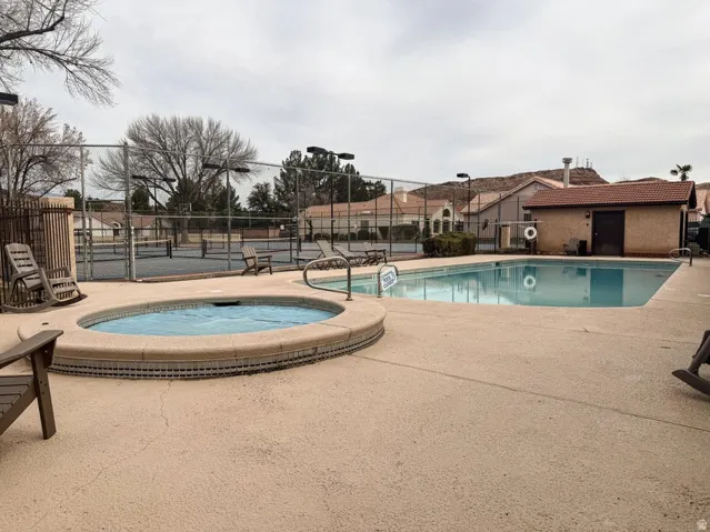 Outdoor leisure area featuring a rectangular swimming pool, a circular spa, and a light-colored concrete deck