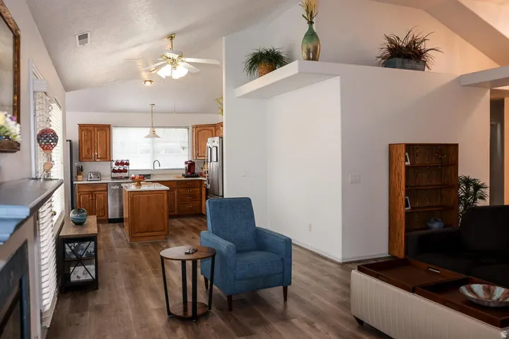 Open-concept living space featuring vaulted ceilings, wood-finish flooring, a kitchen island, and stainless steel appliances