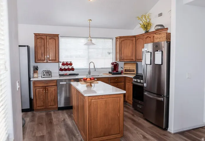 Kitchen featuring warm wood cabinetry, light-toned countertops, and wood-finish flooring