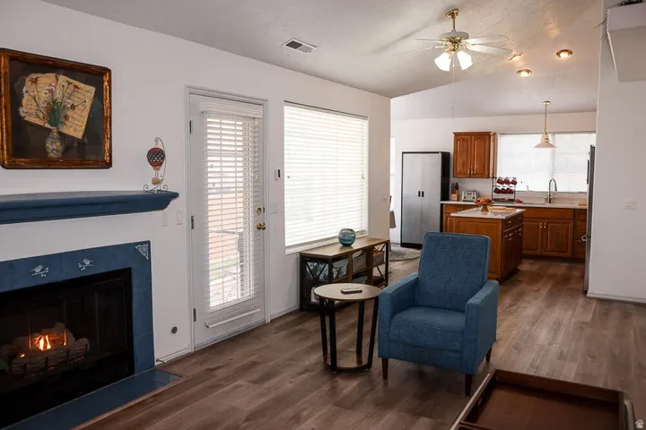 Living area featuring a fireplace with blue tile surround and mantel, wood-finish flooring, a ceiling fan, and recessed lighting