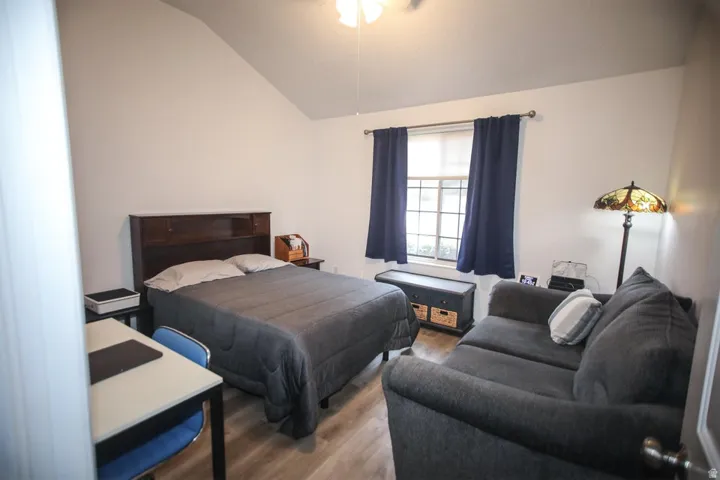 Bedroom featuring wood-finish flooring, vaulted ceiling, and a large window