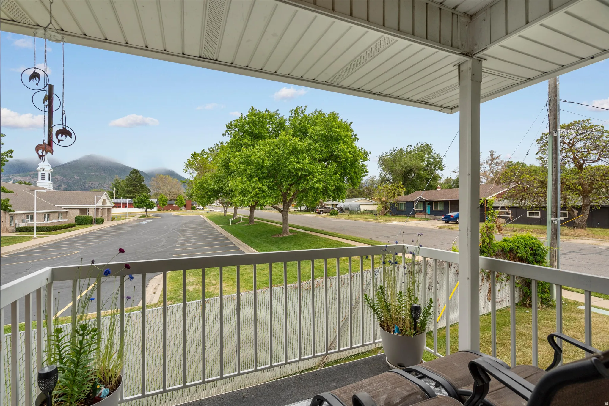 Covered balcony off primary bedroom with white railings and an overhead paneling