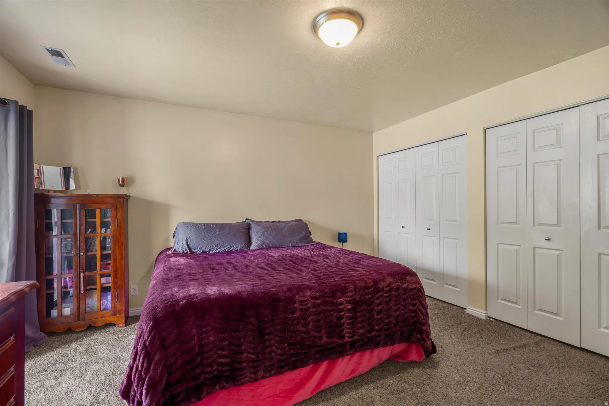 Bedroom featuring neutral wall paint, carpet flooring, a flush-mount ceiling light, and two sets of bi-fold closet doors