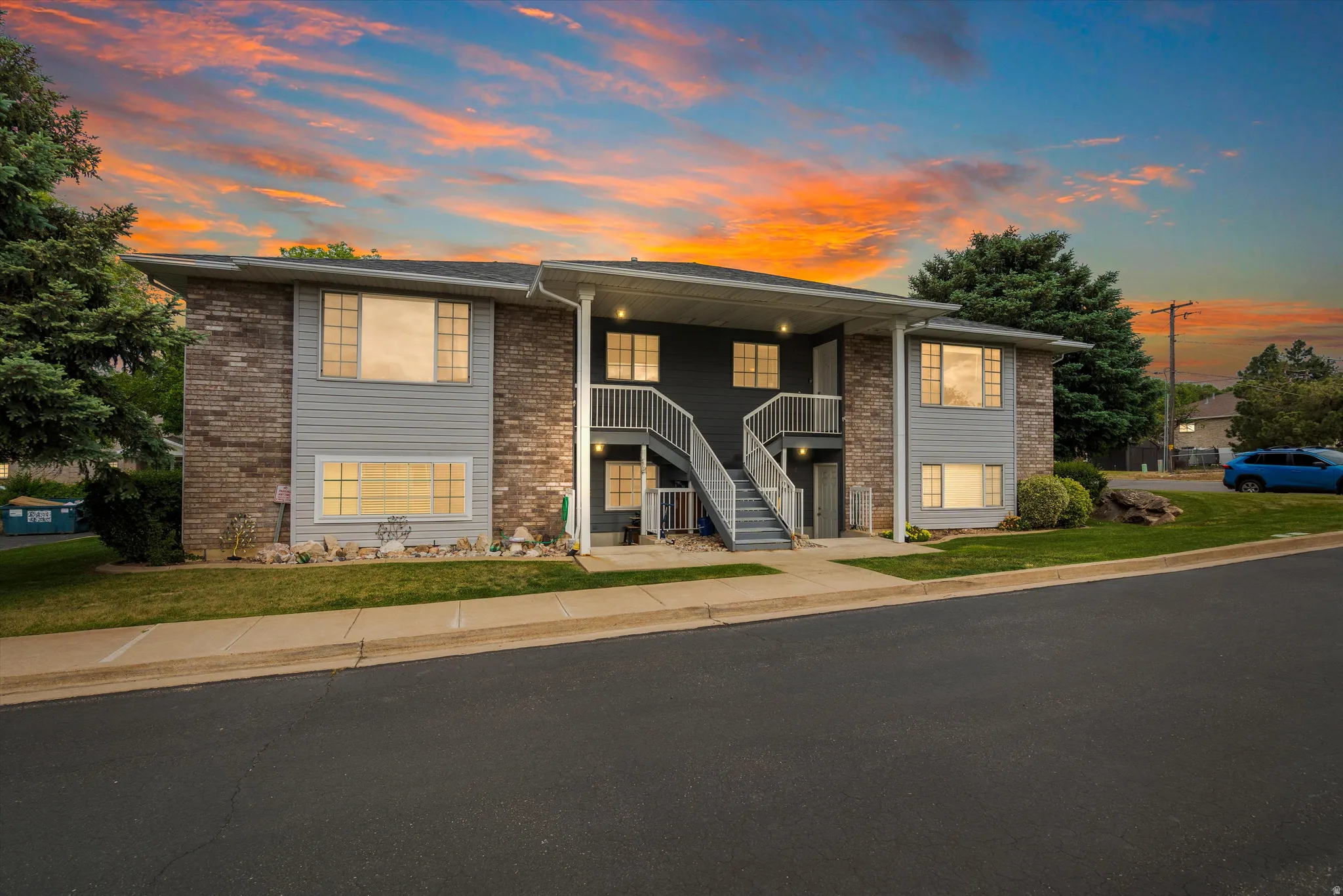 Multi-unit building featuring brick and siding exterior, multiple windows, and a prominent exterior staircase