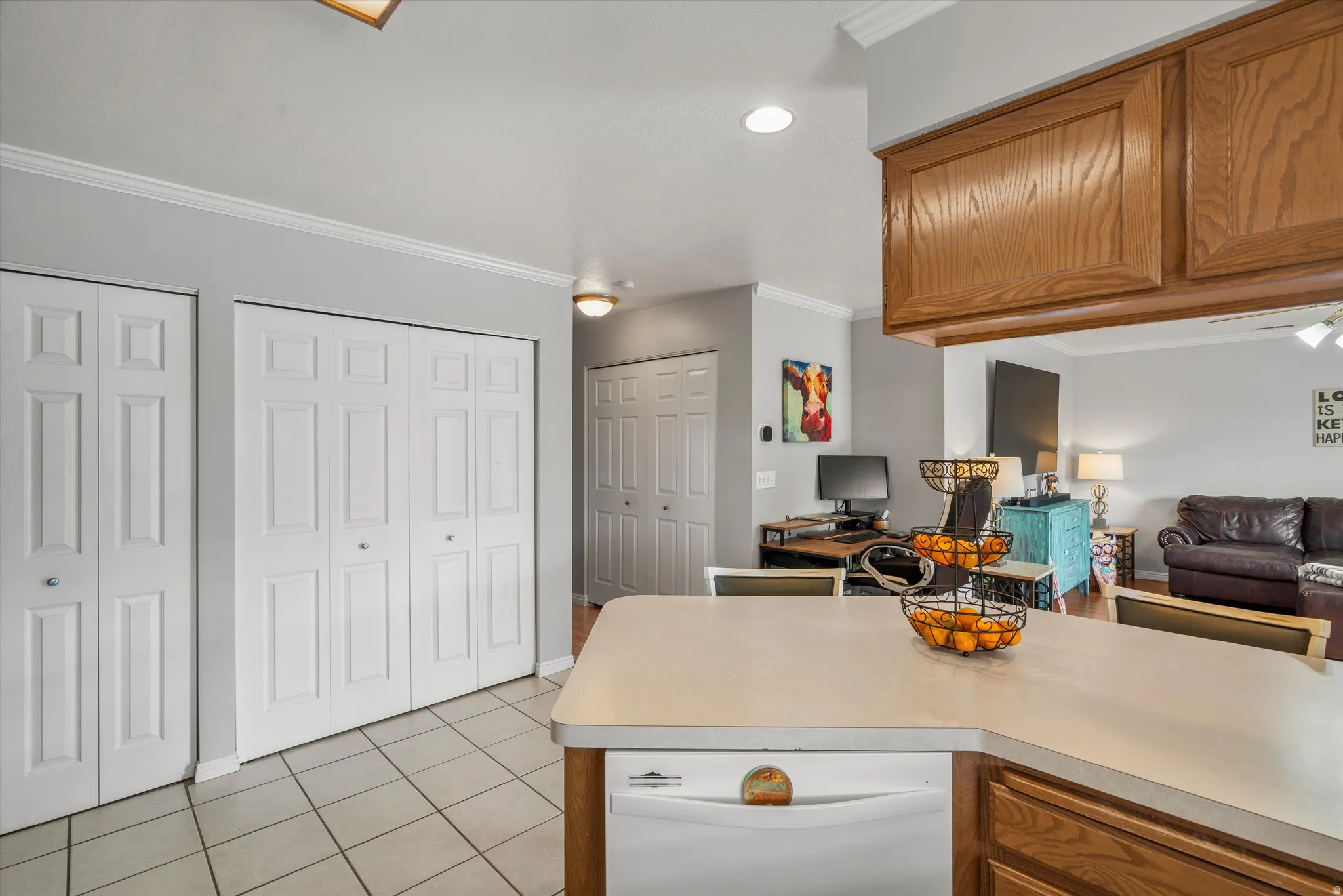 Kitchen peninsula with a light-toned countertop, integrated dishwasher, and wood-finish cabinetry
