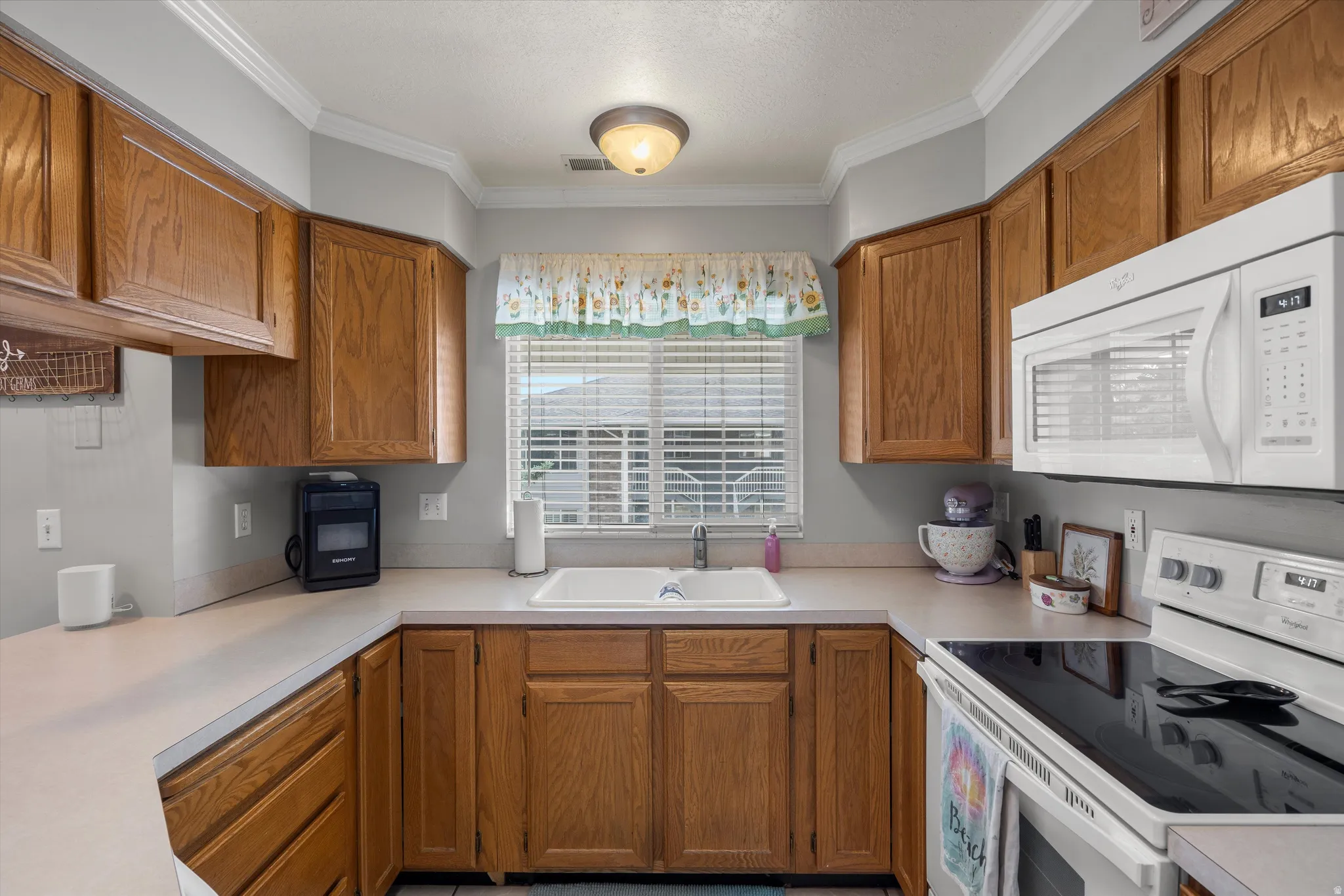 Kitchen featuring wood-finish cabinetry, a built-in microwave, an electric range, and crown molding