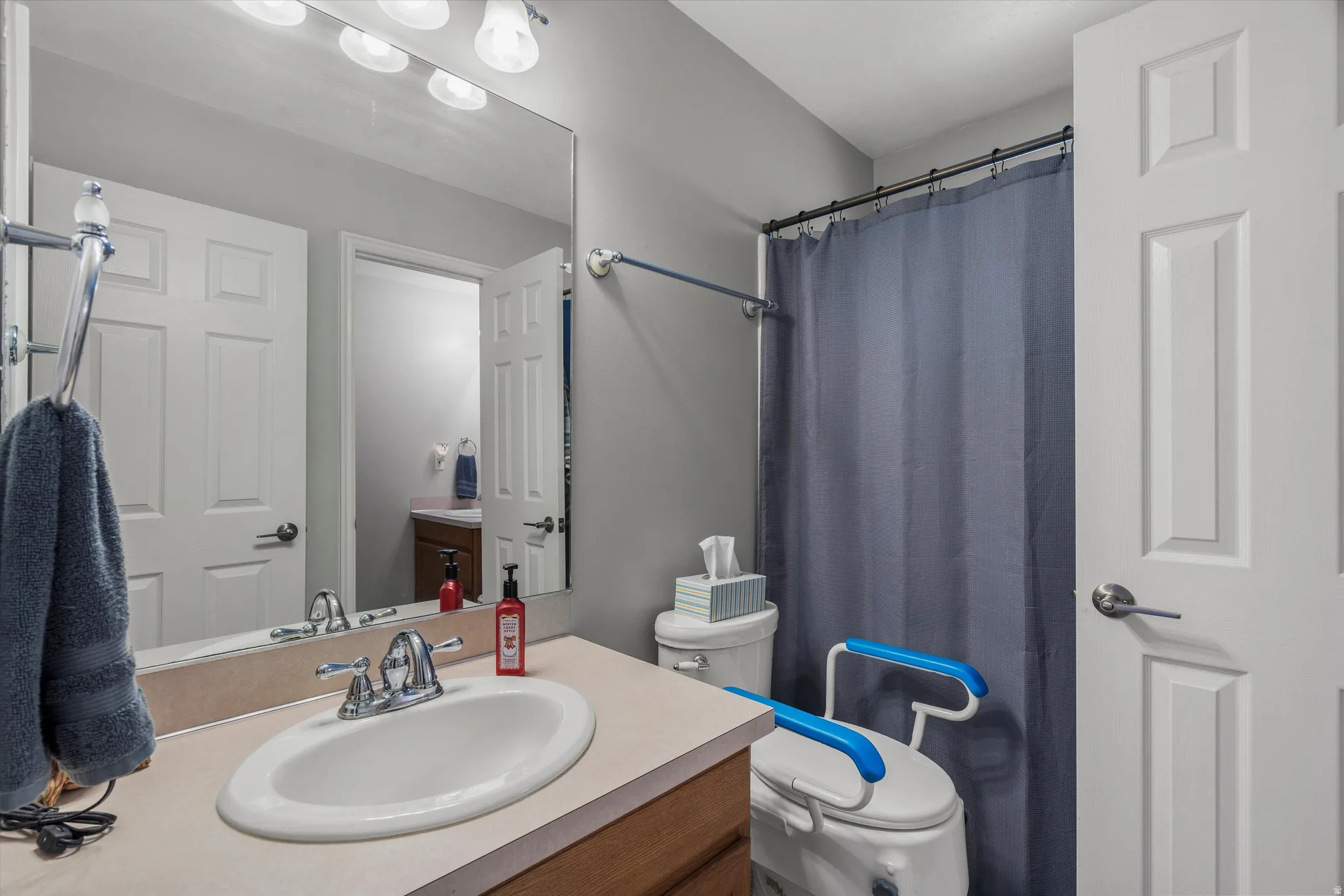 Bathroom featuring a single vanity with an integrated sink, a rectangular mirror, a three-bulb vanity light fixture, and a bathtub