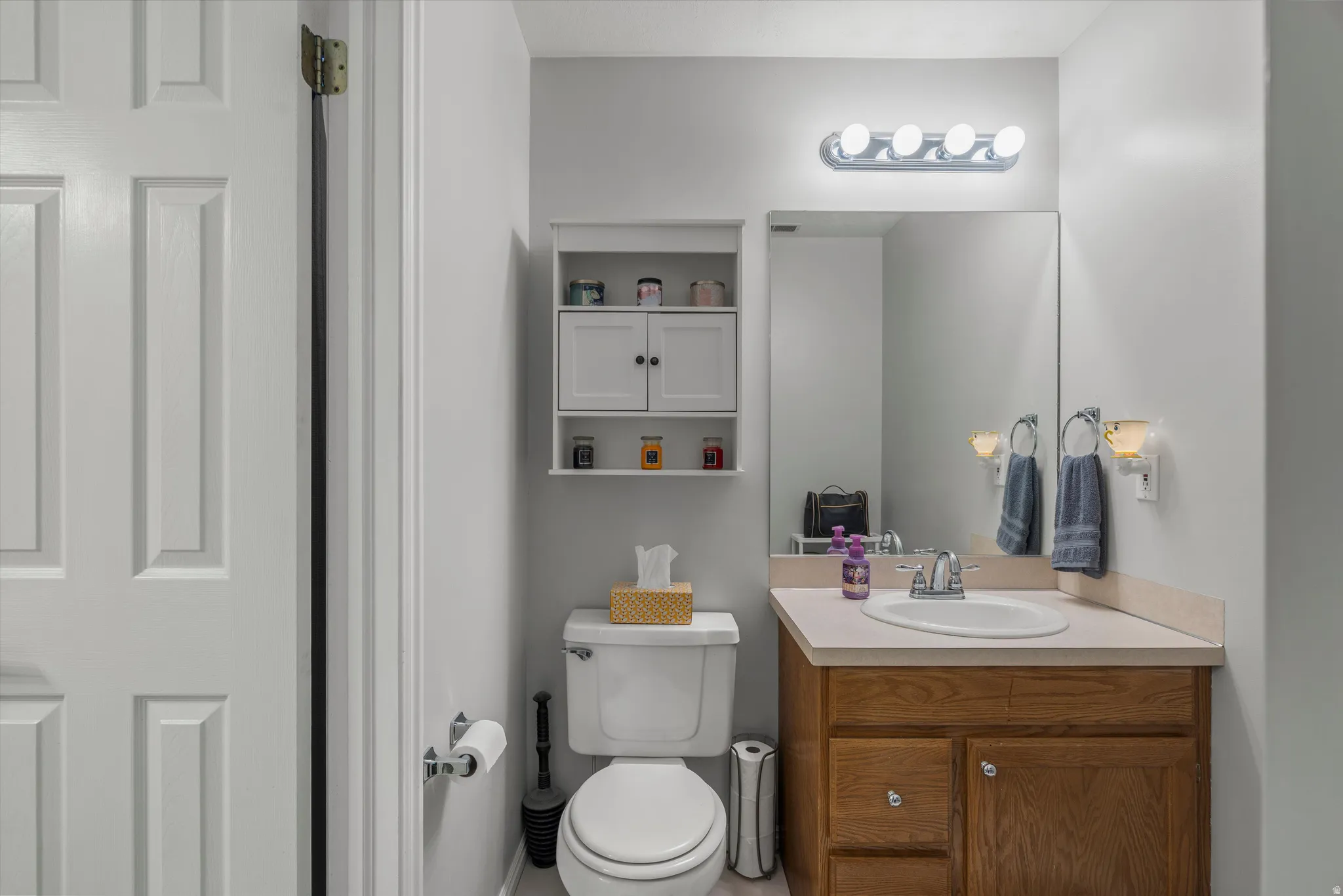 En suite 1/2 Bathroom featuring a wood-finish vanity with a light-toned countertop and sink