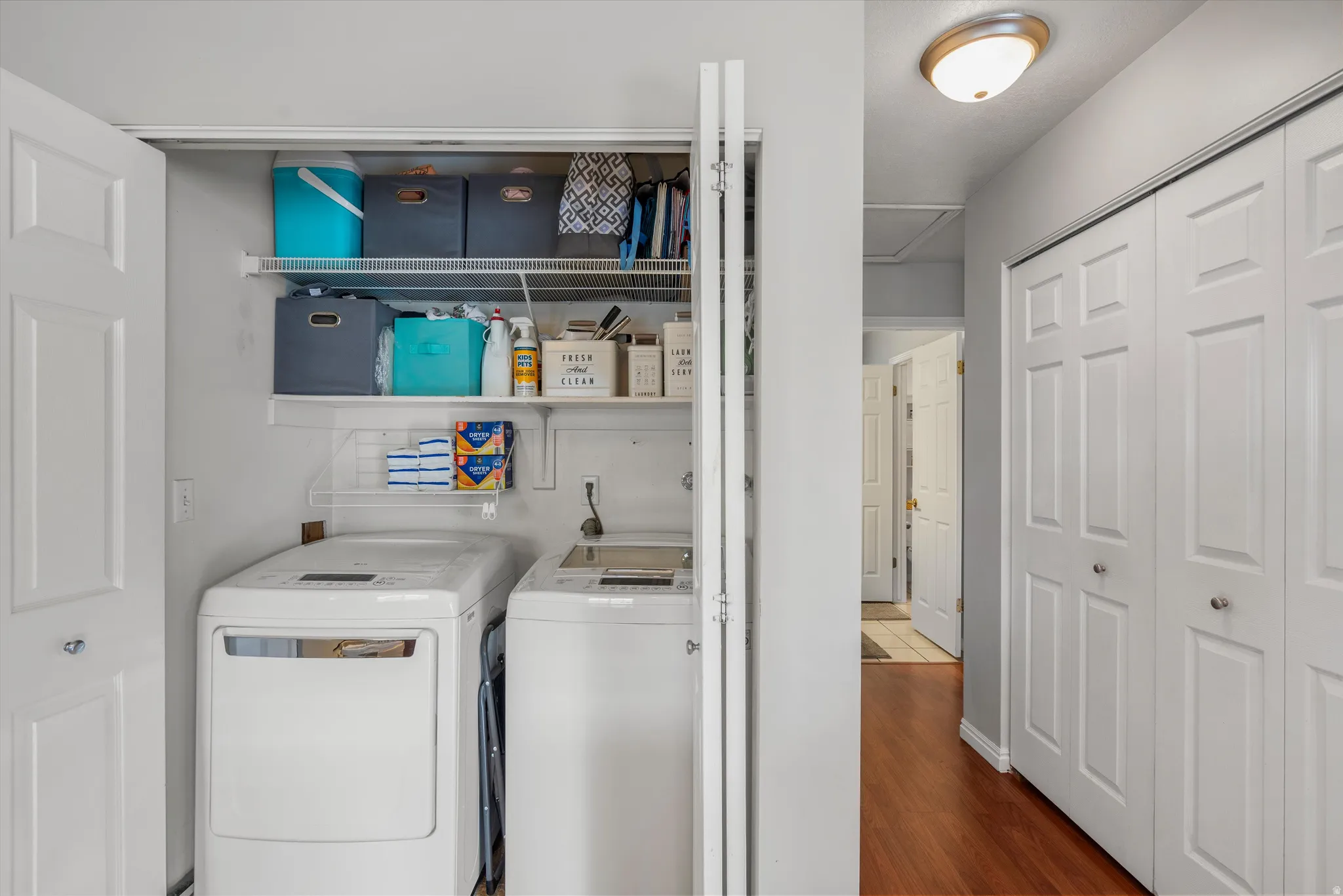 Dedicated laundry closet featuring a built-in top shelf, a wire rack, and bi-fold doors