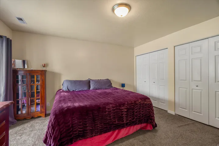 Bedroom featuring neutral wall paint, carpet flooring, a flush-mount ceiling light, and two sets of bi-fold closet doors