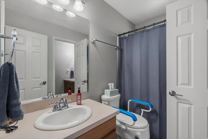Bathroom featuring a single vanity with an integrated sink, a rectangular mirror, a three-bulb vanity light fixture, and a bathtub