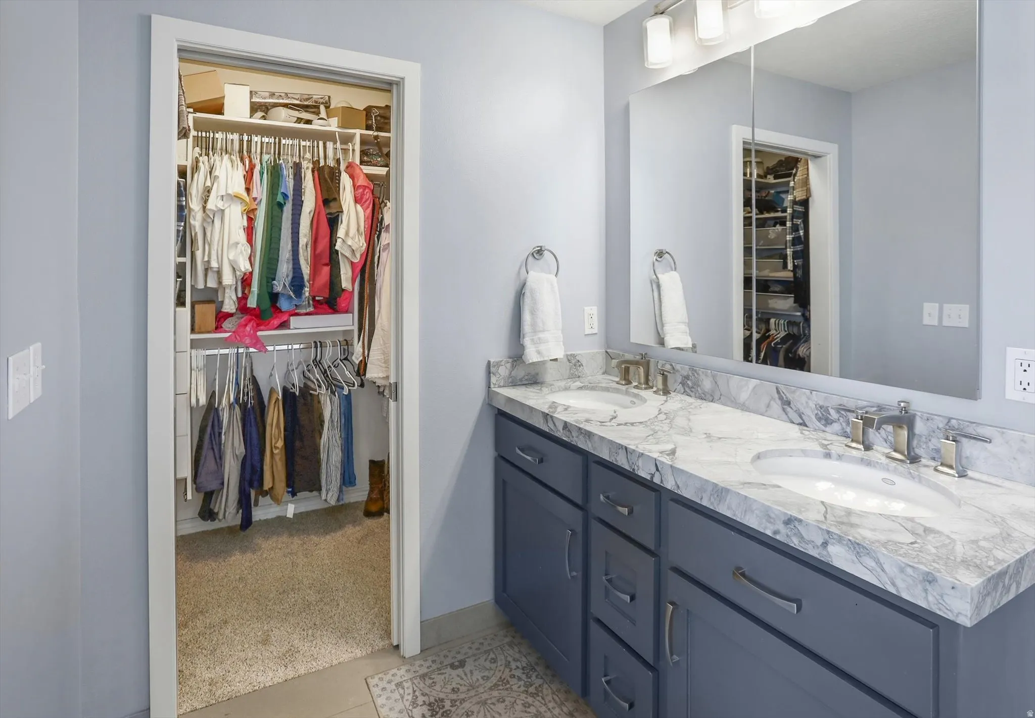 Bathroom vanity featuring dual under-mount sinks, a stone countertop, and blue cabinetry with brushed nickel hardware