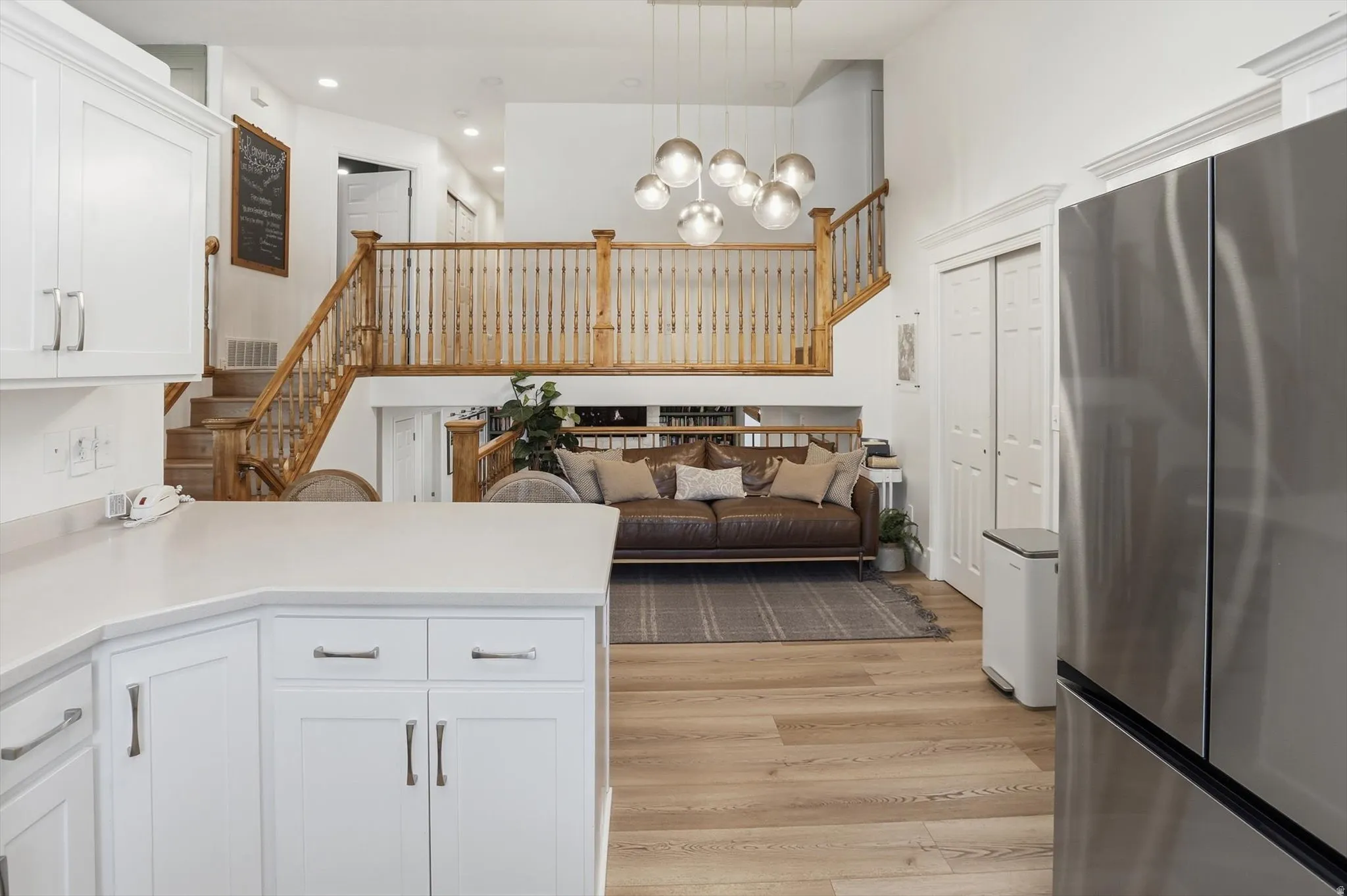 Open-concept living space featuring a two-story ceiling, light wood-finish flooring, and a contemporary multi-orb chandelier