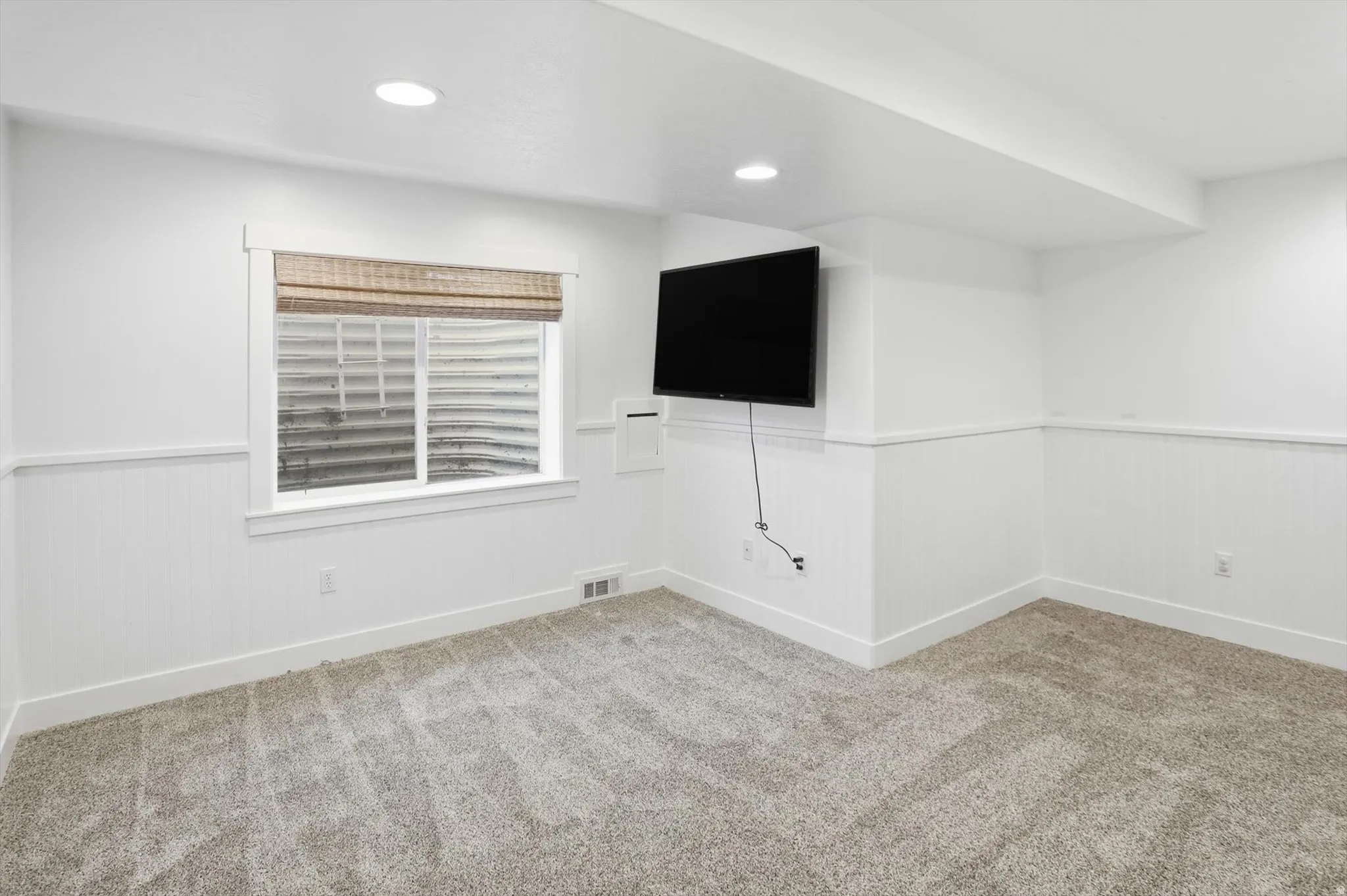 Interior room featuring light-colored carpeting, white board and batten wainscoting, and recessed ceiling lighting