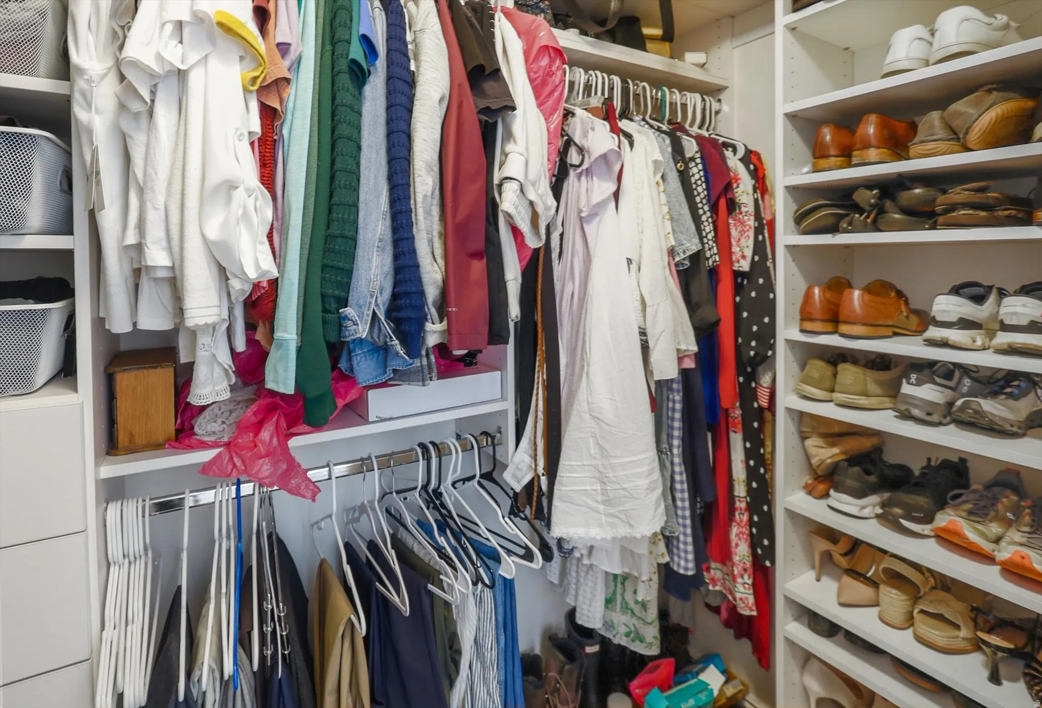 Custom closet organization system featuring multiple hanging rods, integrated shelving, and dedicated shoe storage