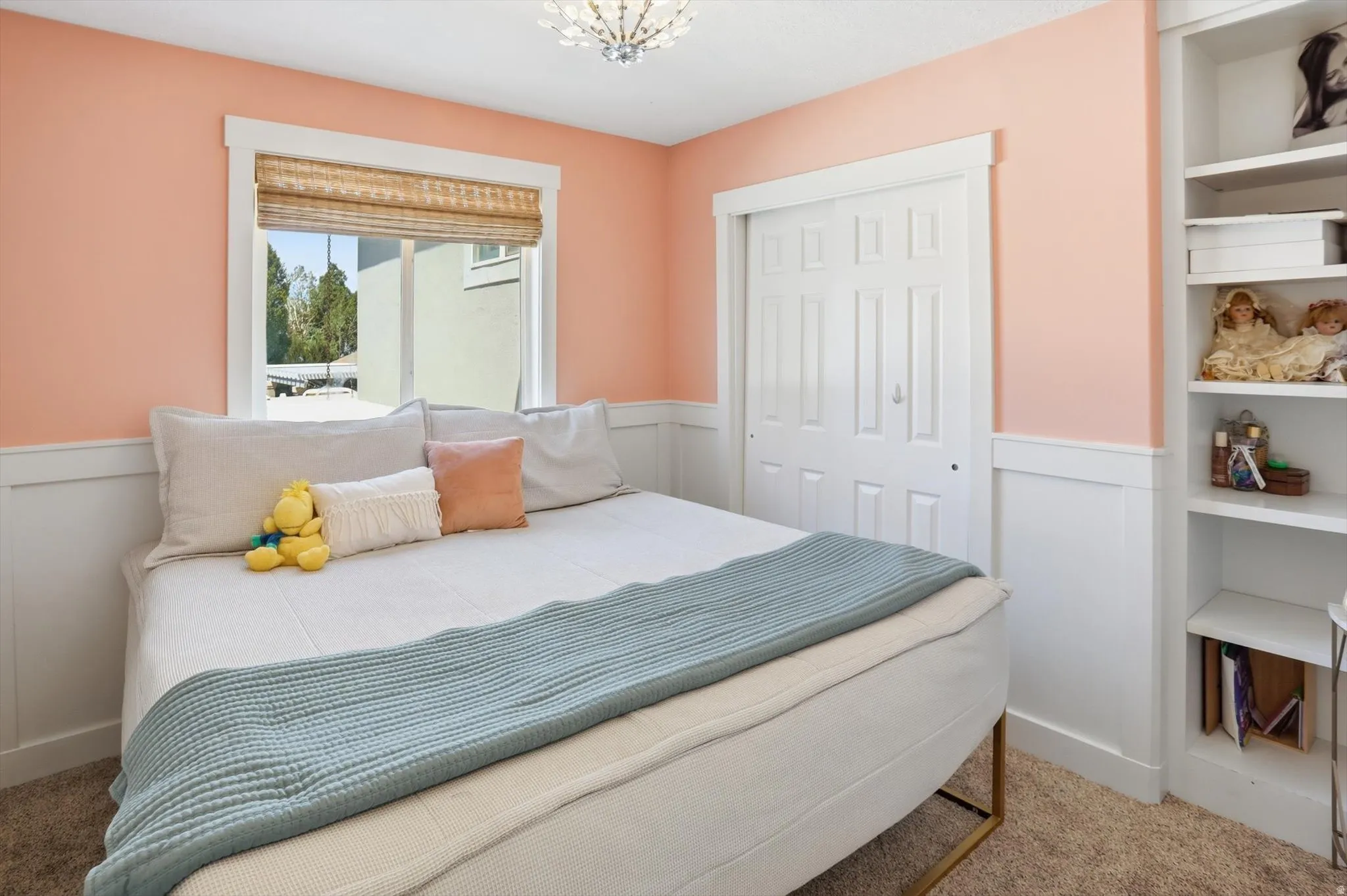 Room featuring a window with woven shades, a built-in closet with bifold doors, and integrated shelving