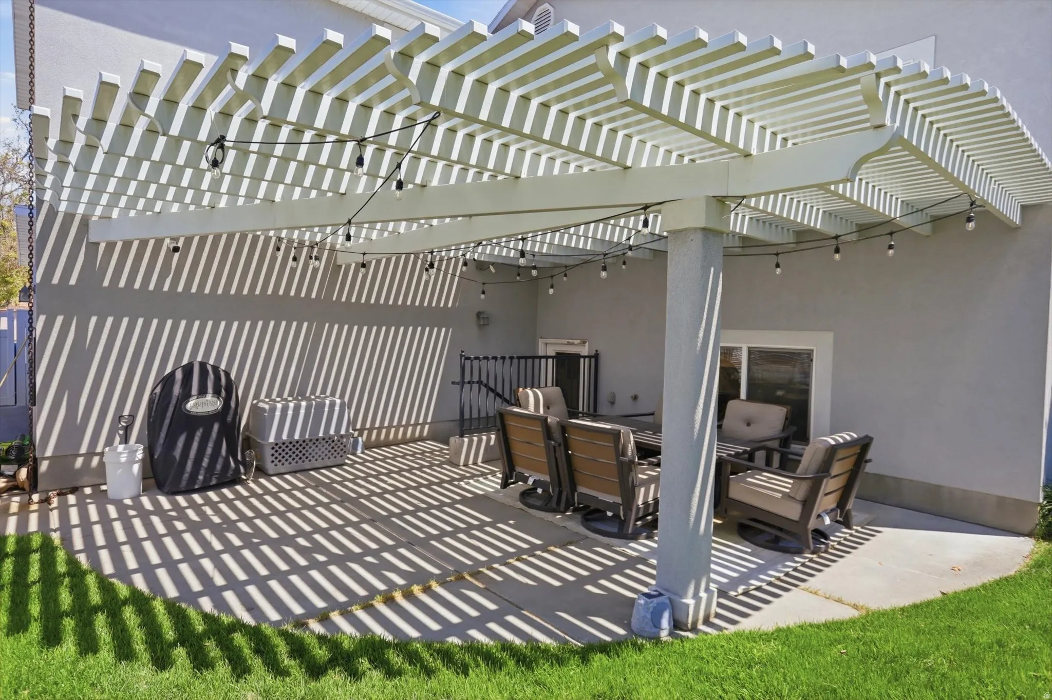 Expansive patio featuring a white pergola with integrated string lighting