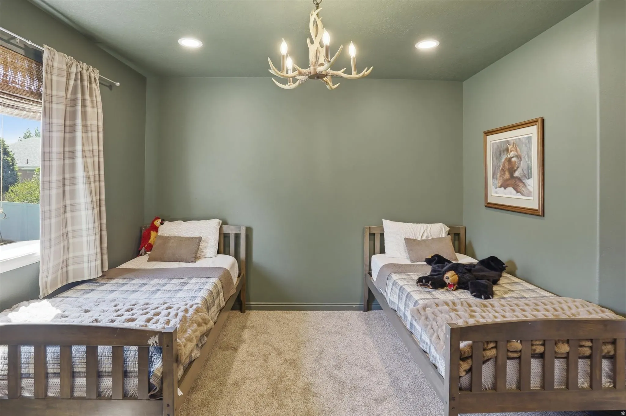 Bedroom featuring two wood-frame beds, plush carpet flooring, and sage green walls