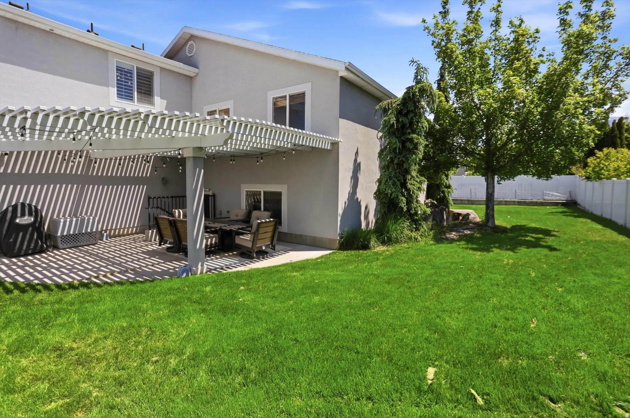 Expansive green lawn with a white privacy fence and mature trees
