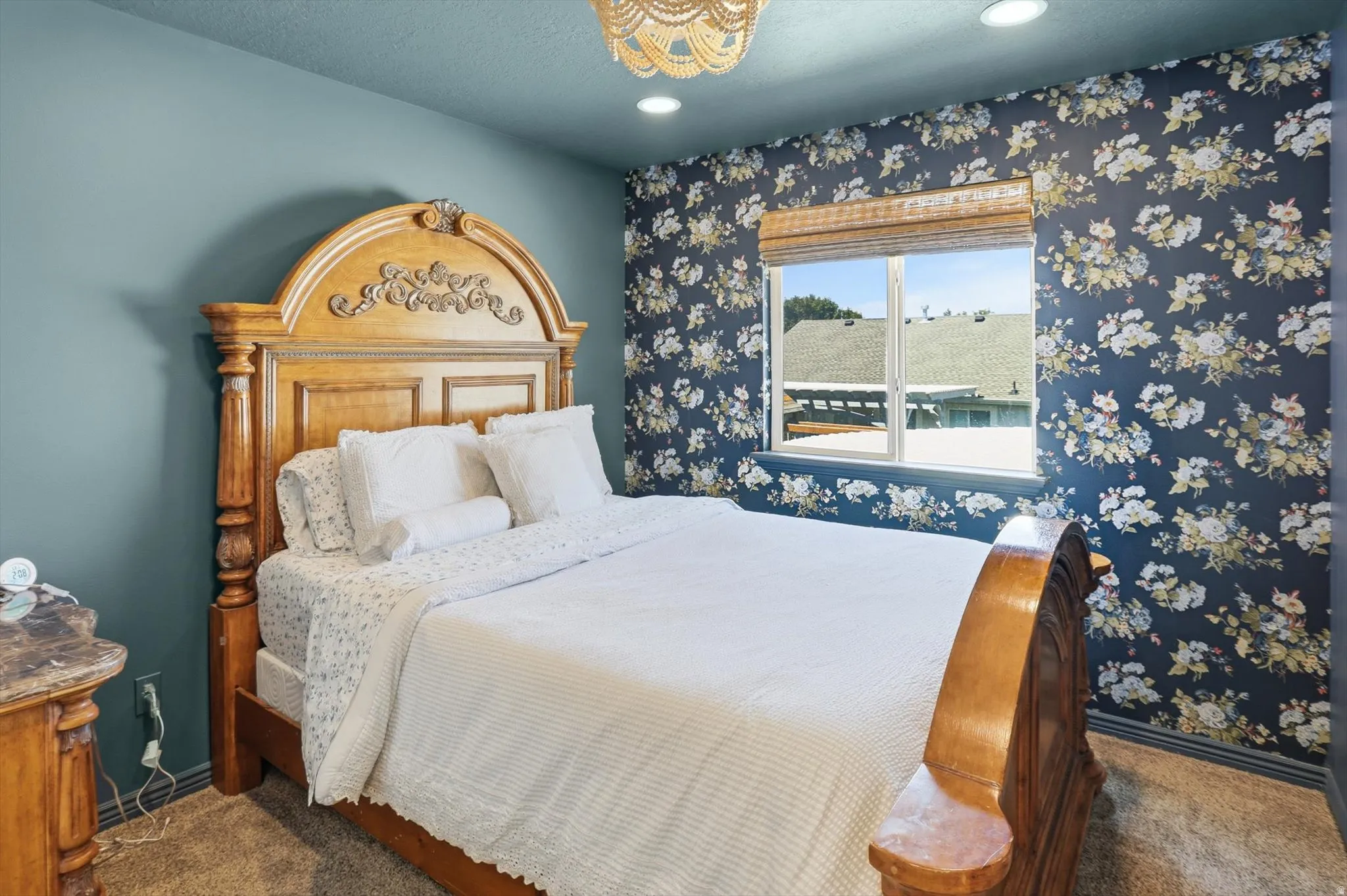 Bedroom featuring a floral accent wall, recessed lighting, and a window with a woven wood shade