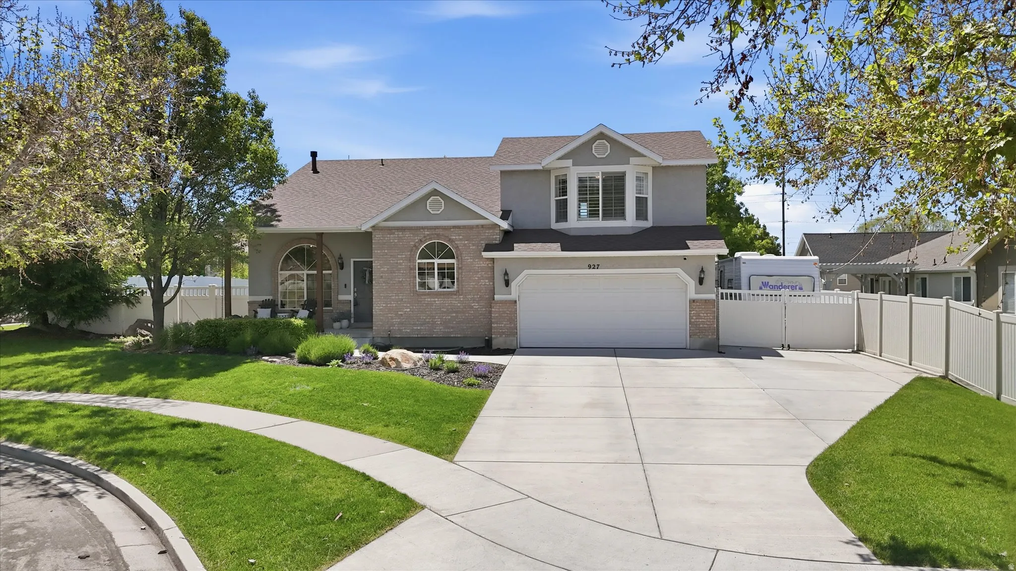 Two-story residence featuring a gray and brick facade with a prominent two-car garage