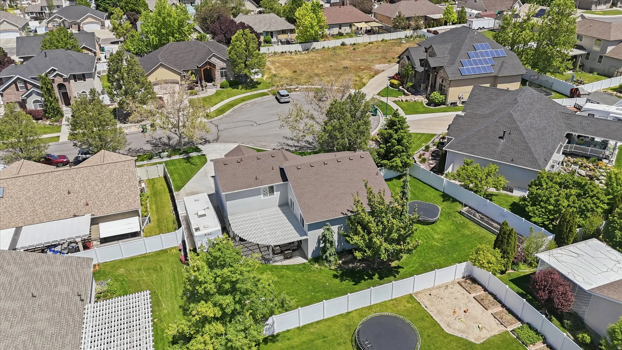 Expansive backyard featuring a manicured lawn, established trees, and a white privacy fence