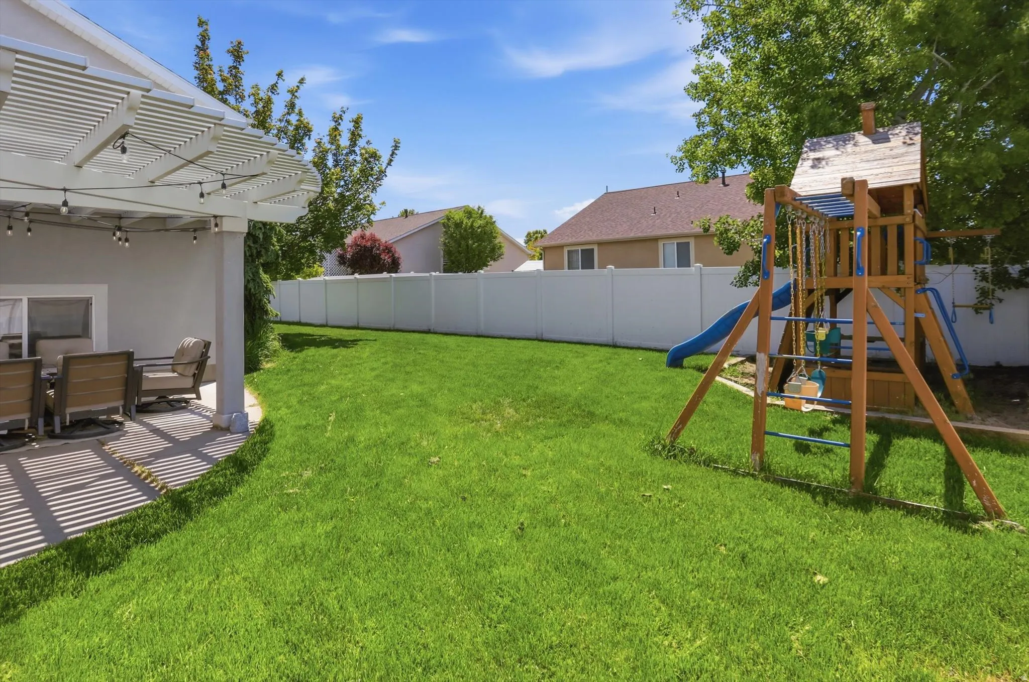 Expansive green lawn with a white privacy fence