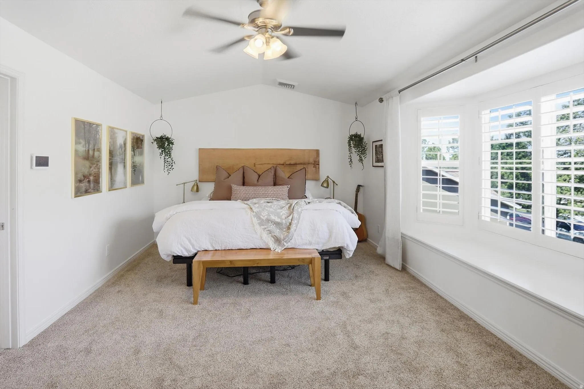 Spacious room featuring vaulted ceilings, a ceiling fan with integrated lighting, plush carpeting, and a built-in window bench with plantation shutters