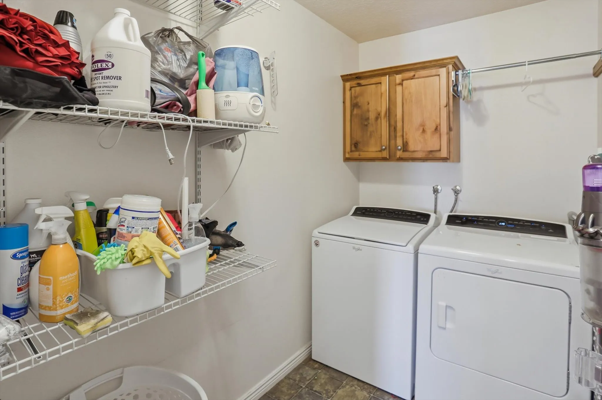 Dedicated laundry area featuring a white washer and dryer, wood-finish wall cabinetry, an overhead hanging rod, and extensive wire shelving