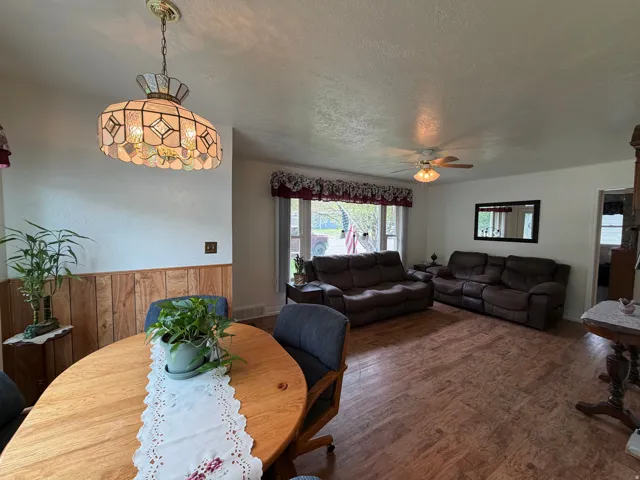 Spacious living area featuring wood-finish flooring, a ceiling fan, and a large window