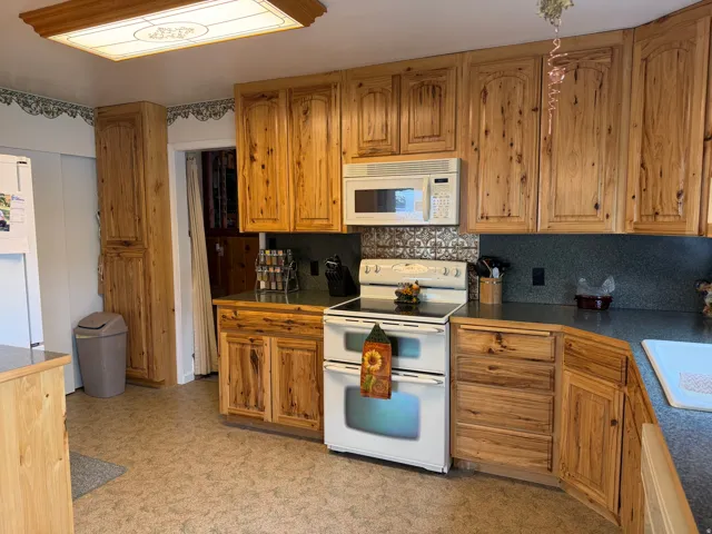 Kitchen featuring wood-finish cabinetry, solid surface countertops, a mosaic tile backsplash, and a built-in microwave above the range