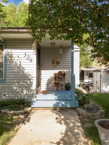 Front entrance featuring a covered porch with a light blue finish, complementing the light-colored siding