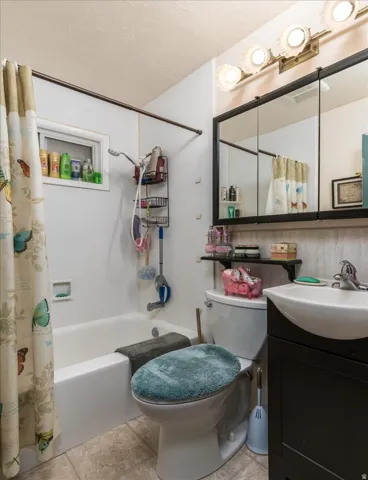 Full bathroom featuring a white bathtub, white toilet, and a dark vanity with an integrated sink