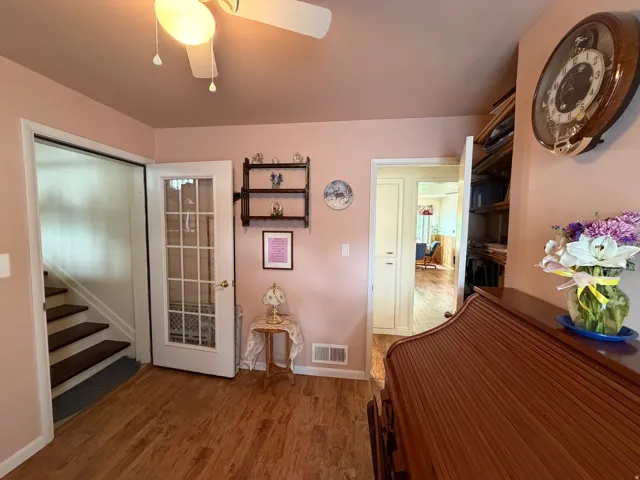Warm interior space featuring wood-finish flooring, a ceiling fan with light fixture, and a white French door