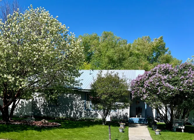 Front exterior featuring a light blue metal roof, horizontal siding, and a concrete pathway