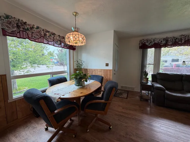 Spacious dining area featuring wood-finish flooring, wainscoting, and large windows