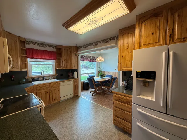 Kitchen featuring wood cabinetry, dark countertops, a built-in electric range, and a white side-by-side refrigerator