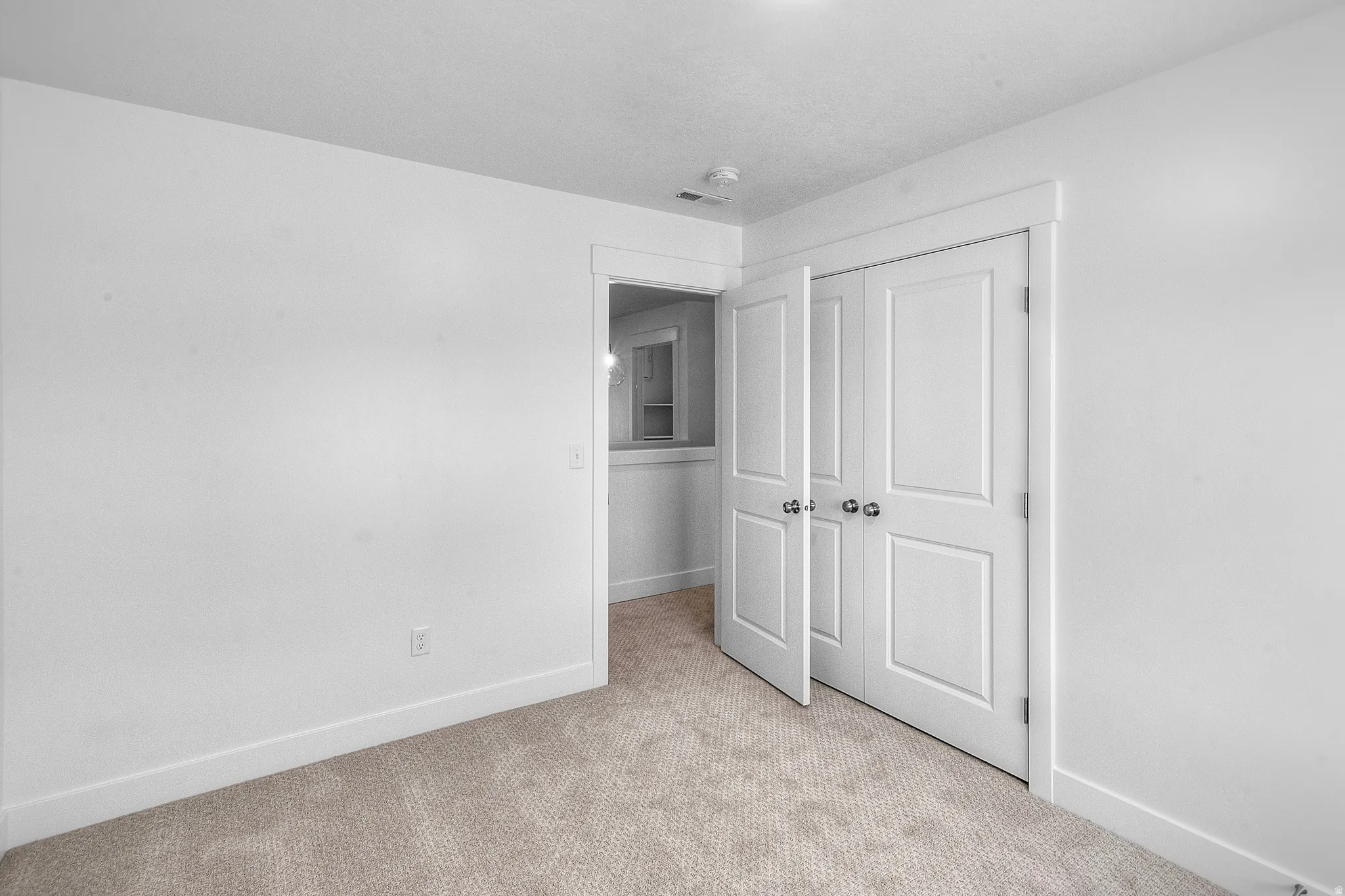 Neutral toned carpeted room featuring a white paneled bi-fold door closet with chrome hardware