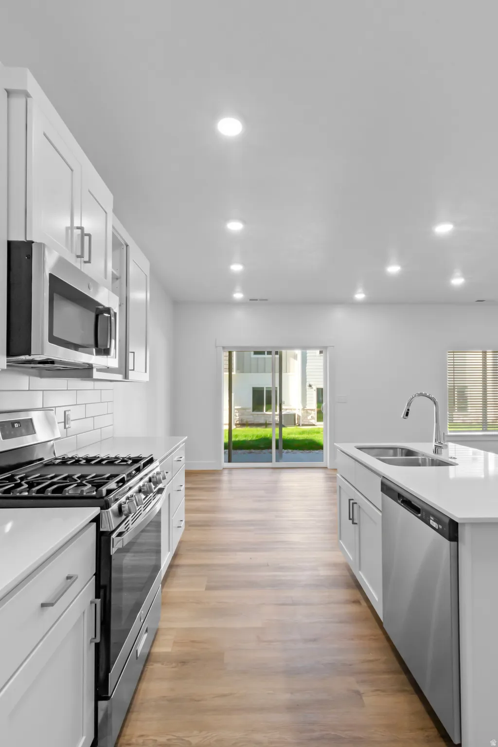 Modern kitchen featuring white cabinetry, stainless steel appliances, light-toned wood-finish flooring, and recessed lighting