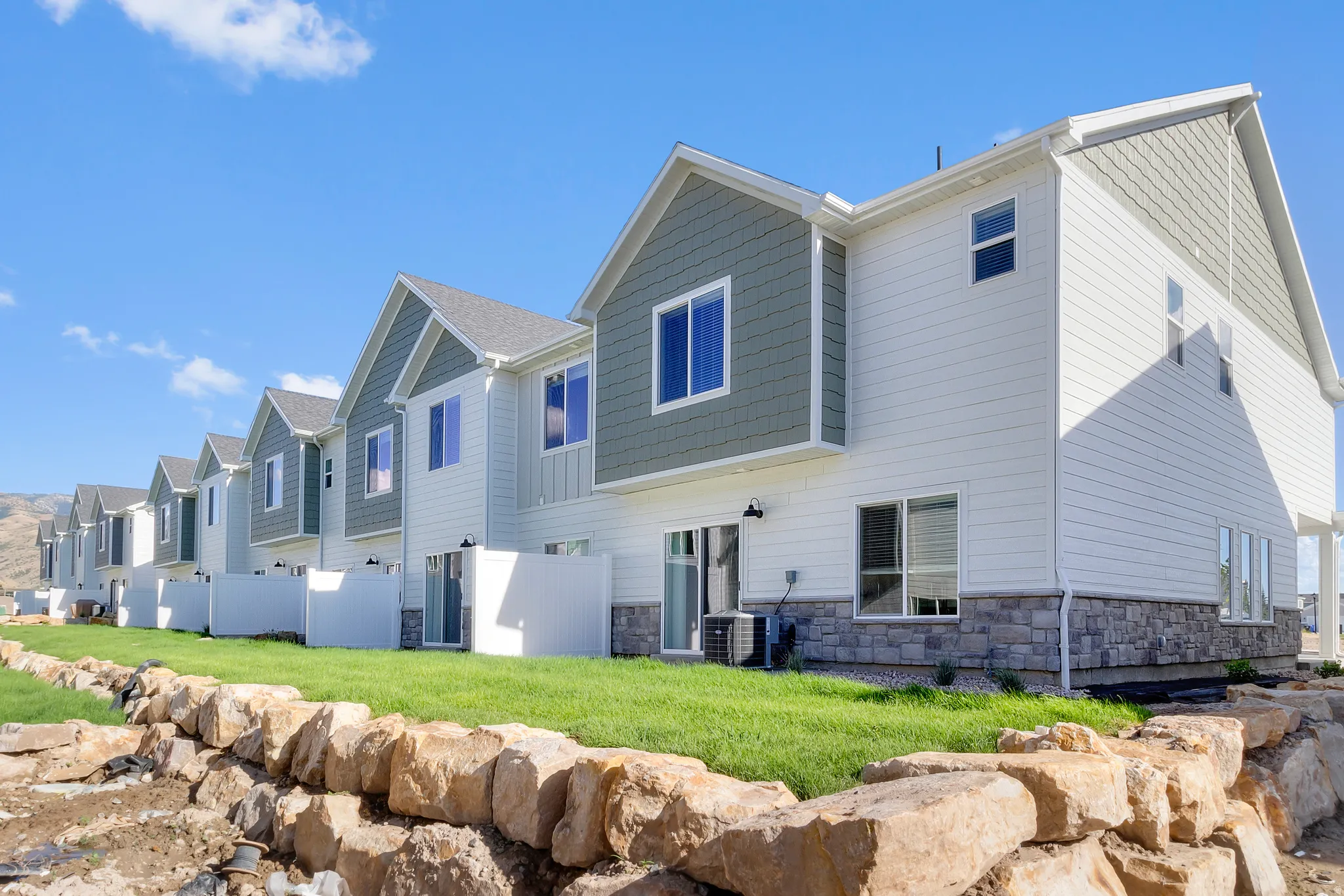 Modern townhome exteriors featuring horizontal siding, decorative shingles, and stone veneer accents