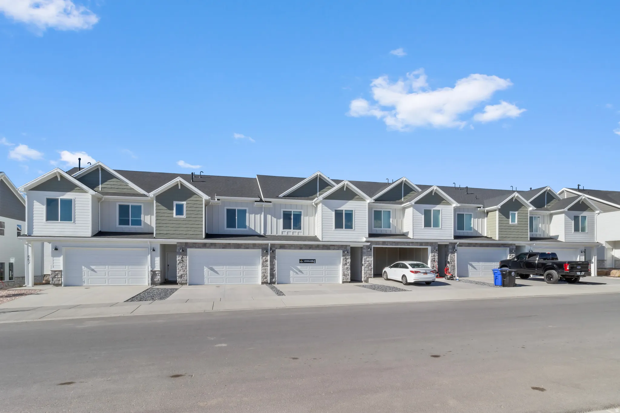 Modern townhome exterior featuring clean architectural lines, mixed siding, attached garages, and individual covered entrances