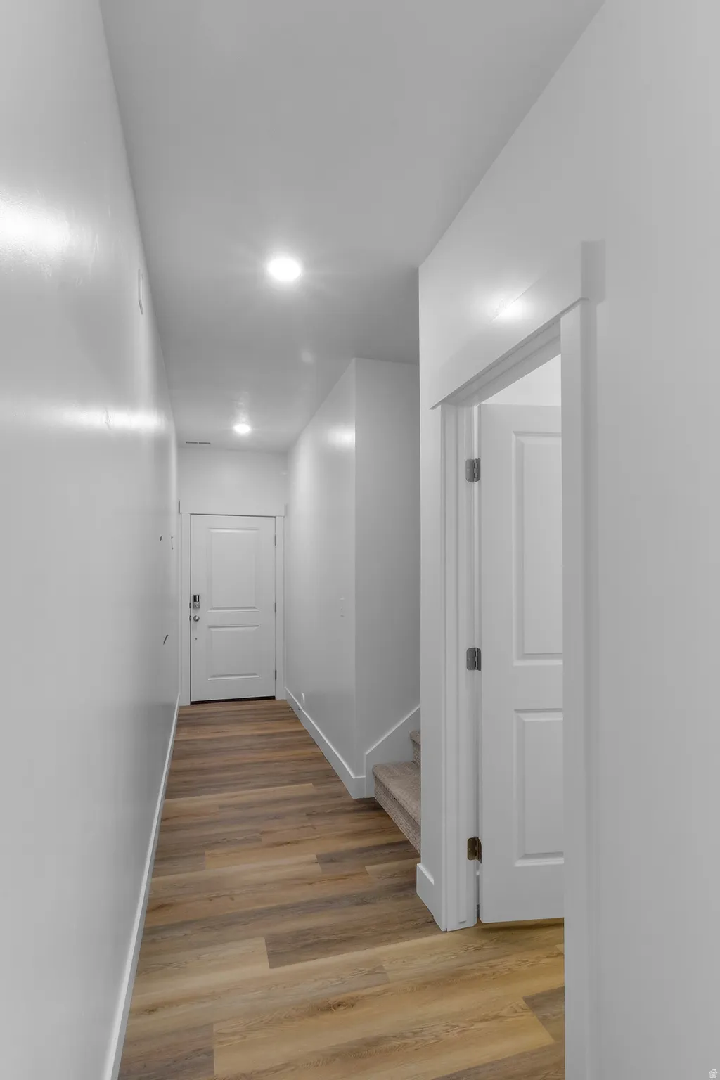 Hallway featuring wood-finish flooring, recessed lighting, and white paneled doors