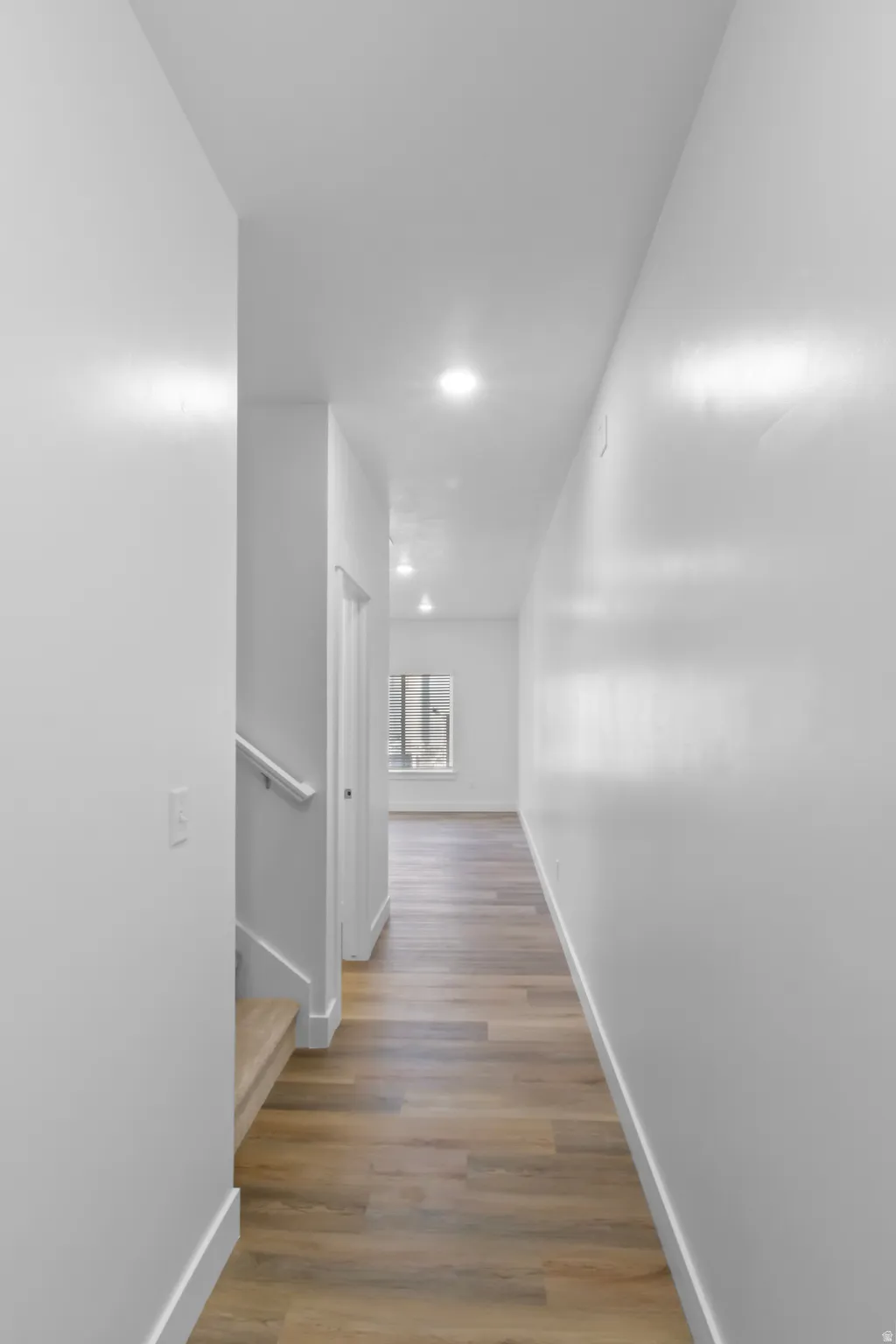 Hallway with wood-finish flooring, recessed lighting, and white baseboards