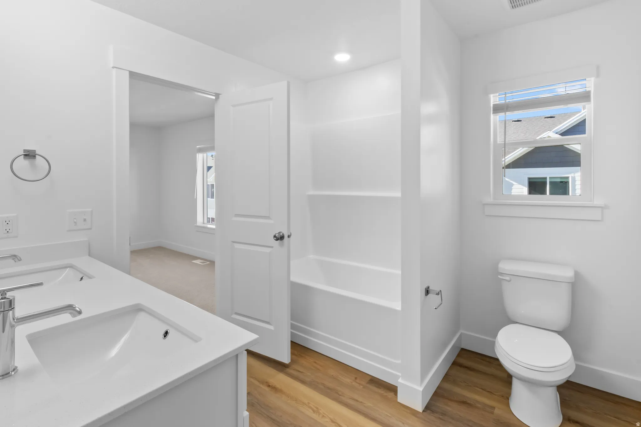 Bright bathroom featuring a dual vanity with white countertops, integrated sinks, and chrome fixtures